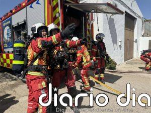 Bomberos extinguen un incendio en 13 vehículos pesados y material en desuso en un recinto al aire libre en Parla